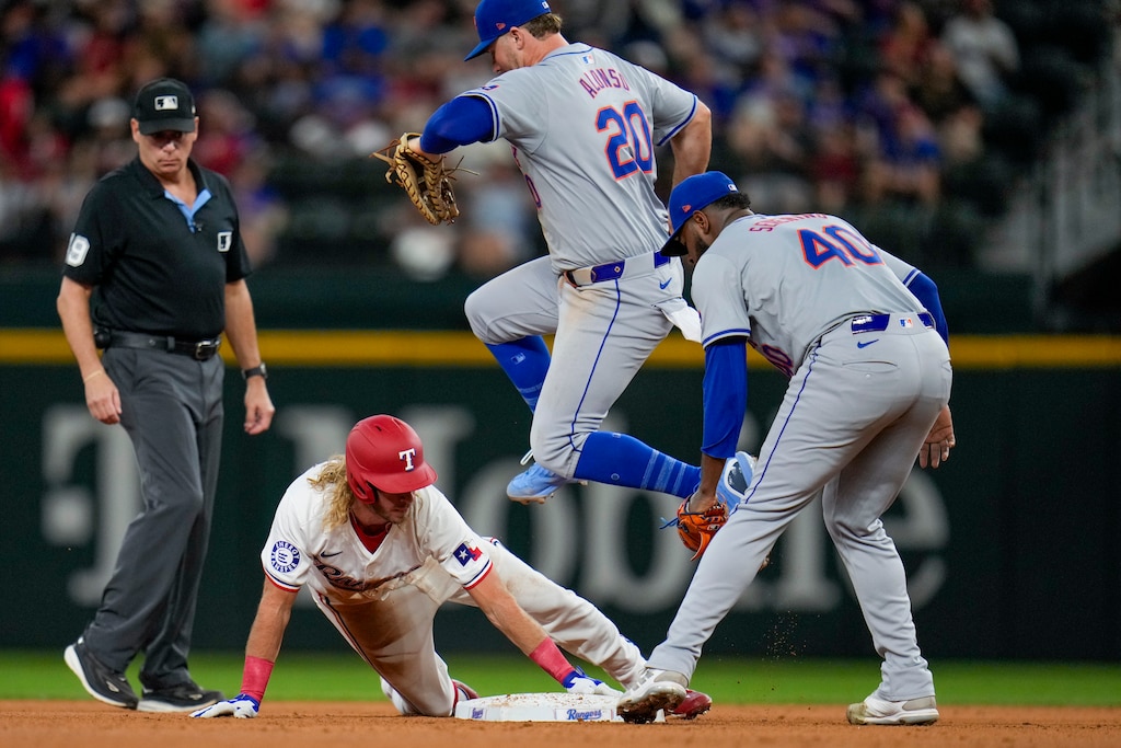 New York Mets first base Pete Alonso (20) leaps over Texas Rangers' Travis Jankowski, bottom, while attempting to tag him out during the fourth inning of a baseball game, Tuesday, June 18, 2024, in Arlington, Texas. Looking on are Mets starting pitcher Luis Severino (40) and second base umpire Andy Fletcher.
