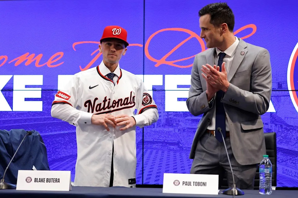 Nationals manager Blake Butera (L) puts on his jersey alongside Nationals general manager and president of baseball operations Paul Toboni (R) at an introductory press conference. IMAGN IMAGES via Reuters Connect