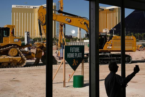 FILE - A person takes a picture near construction equipment during a groundbreaking ceremony for the Athletics' baseball stadium Monday, June 23, 2025, in Las Vegas. (AP Photo/John Locher, File)