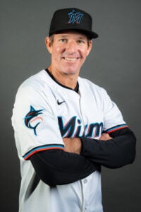 Clayton McCullough, smiling and wearing a Miami Marlins uniform and cap, poses with arms crossed in front of a gray studio backdrop.