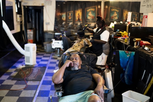 Barber Christopher Fowlkes takes a nap between clients inside of Phaze 2 Barbershop, in Baltimore, Tuesday, August 5, 2025.