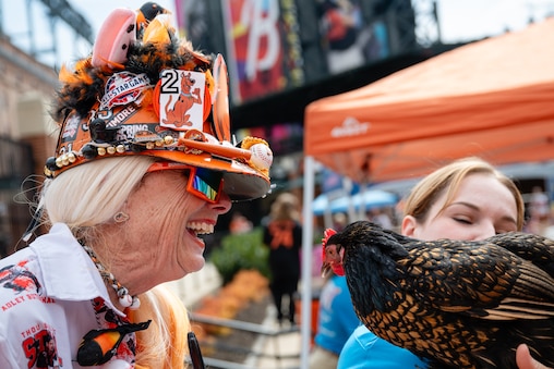 Robin Goodwin sports her custom made Orioles helmet while meeting a chicken at the O's Eutaw Street Block Party on March 29th, 2025 in Baltimore, MD.