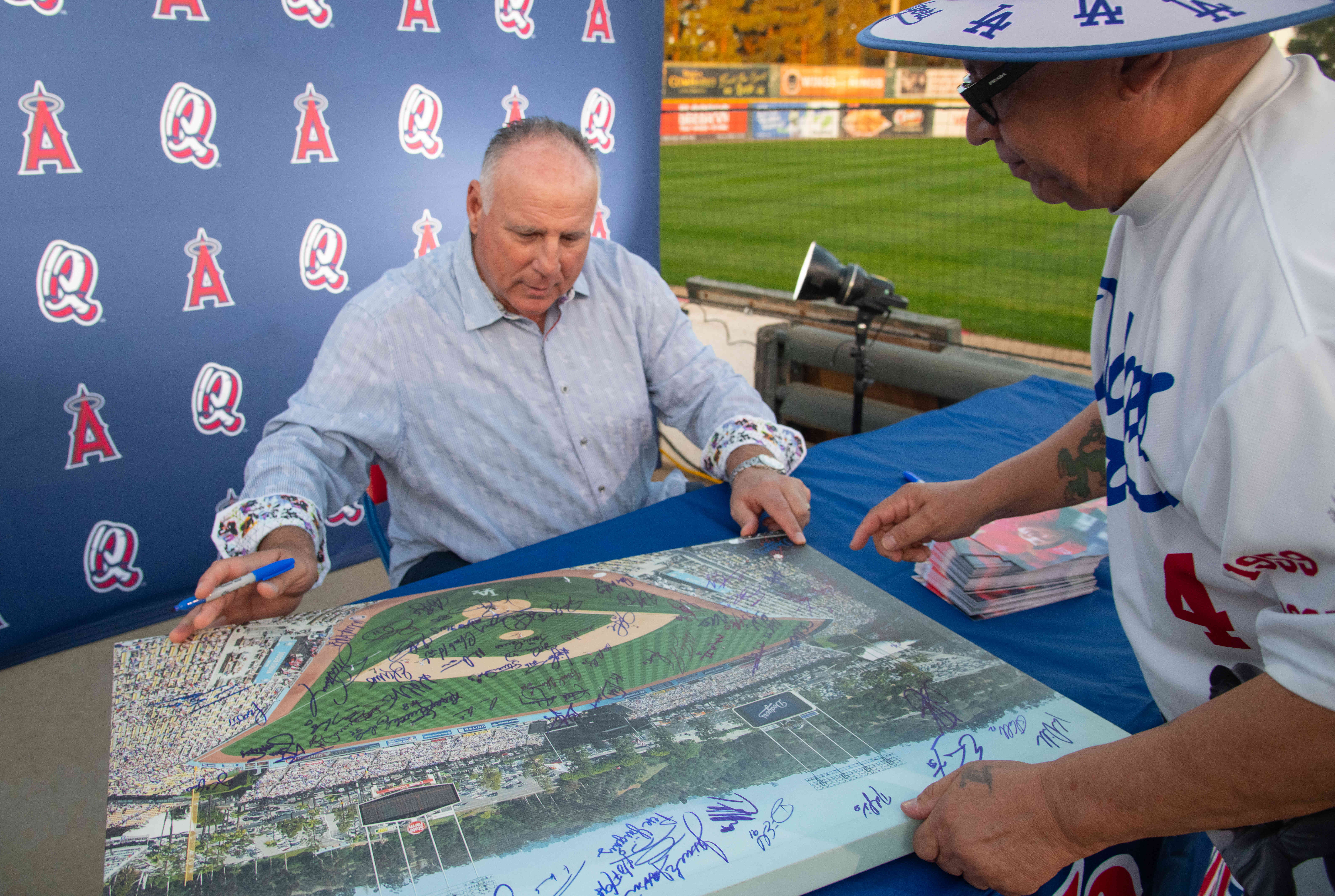 Former Los Angeles Angels manager Mike Scioscia signs a poster...