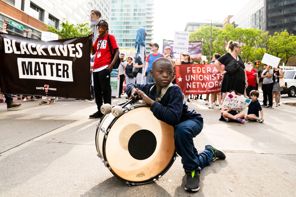 Gavin Lake, 11, with the New Baltimore Christian Warriors, takes a break while marching to McKeldin Plaza from Camden Yards on May 1, 2025. Protesters demanded the administration Stop the Billionaire Takeover and defend unions, social security, health care, and public services.