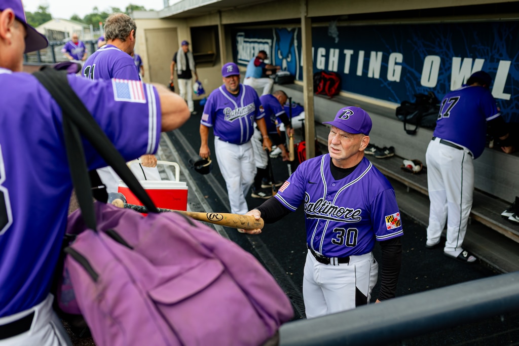 Baltimore City Police Commissioner Richard Worley hands a bat to a teammate before playing in an over 40 league, at Harford Sports Complex in Bel Air, MD on Sunday, June 22, 2025.