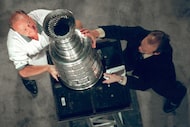 Stars owner Tom Hicks receives assistance from broadcaster Ralph Strangis to put the Stanley...