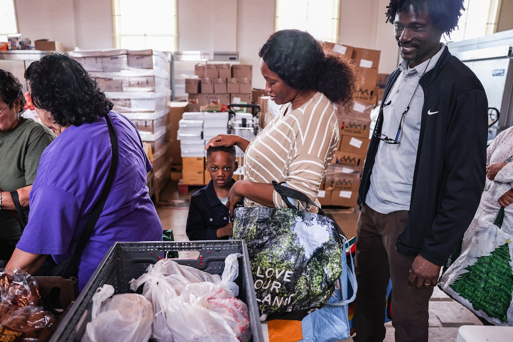 Adama Bangura, 42, and her husband, Kasim Deen, 47, wait in line with their 4-year-old son to collect food during a weekly distribution event at Hughes United Methodist Church on Tuesday, Aug. 5, 2025, in Montgomery County, Md. Recent ICE raids on a food pantry and local businesses have sparked fear among immigrant communities throughout the county.
