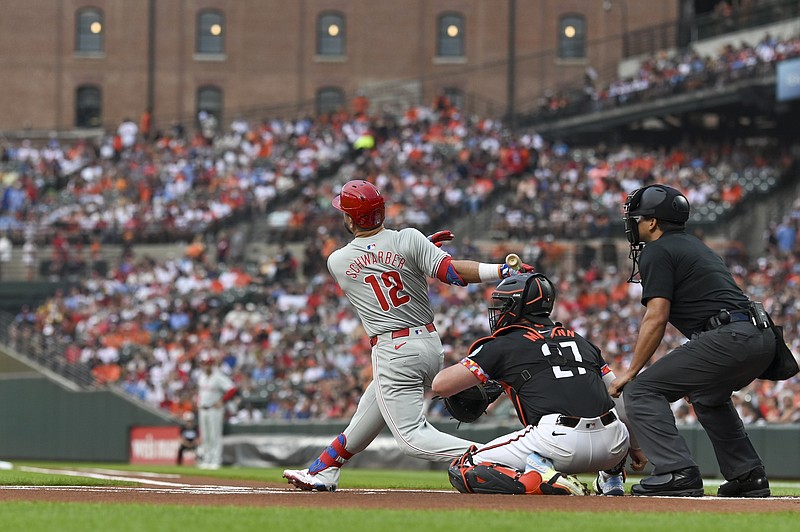 Jun 14, 2024; Baltimore, Maryland, USA; Philadelphia Phillies designated hitter Kyle Schwarber (12) hits a solo home run in the first inning against the Baltimore Orioles at Oriole Park at Camden Yards. Mandatory Credit: Tommy Gilligan-USA TODAY Sports