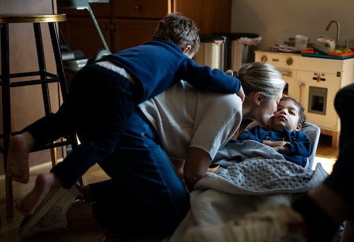 Albert Akras jumps on his mother Annie Akras’ back while she kisses her daughter Carmen Akras inside of their home in Baltimore, Friday, November 7, 2025.
