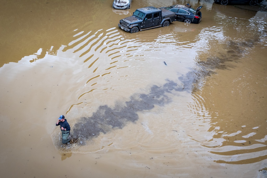 Aaron Fitzgerald wades through the flooded parking lot of Westernport Elementary School to retrieve belongings from his mother waterlogged car after a catastrophic storm hit the area on Tuesday.