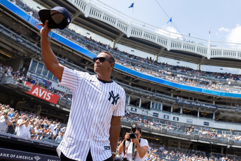 Alex Rodriguez salutes fans, holding his baseball cap in the air, during Old Timer’s Day.