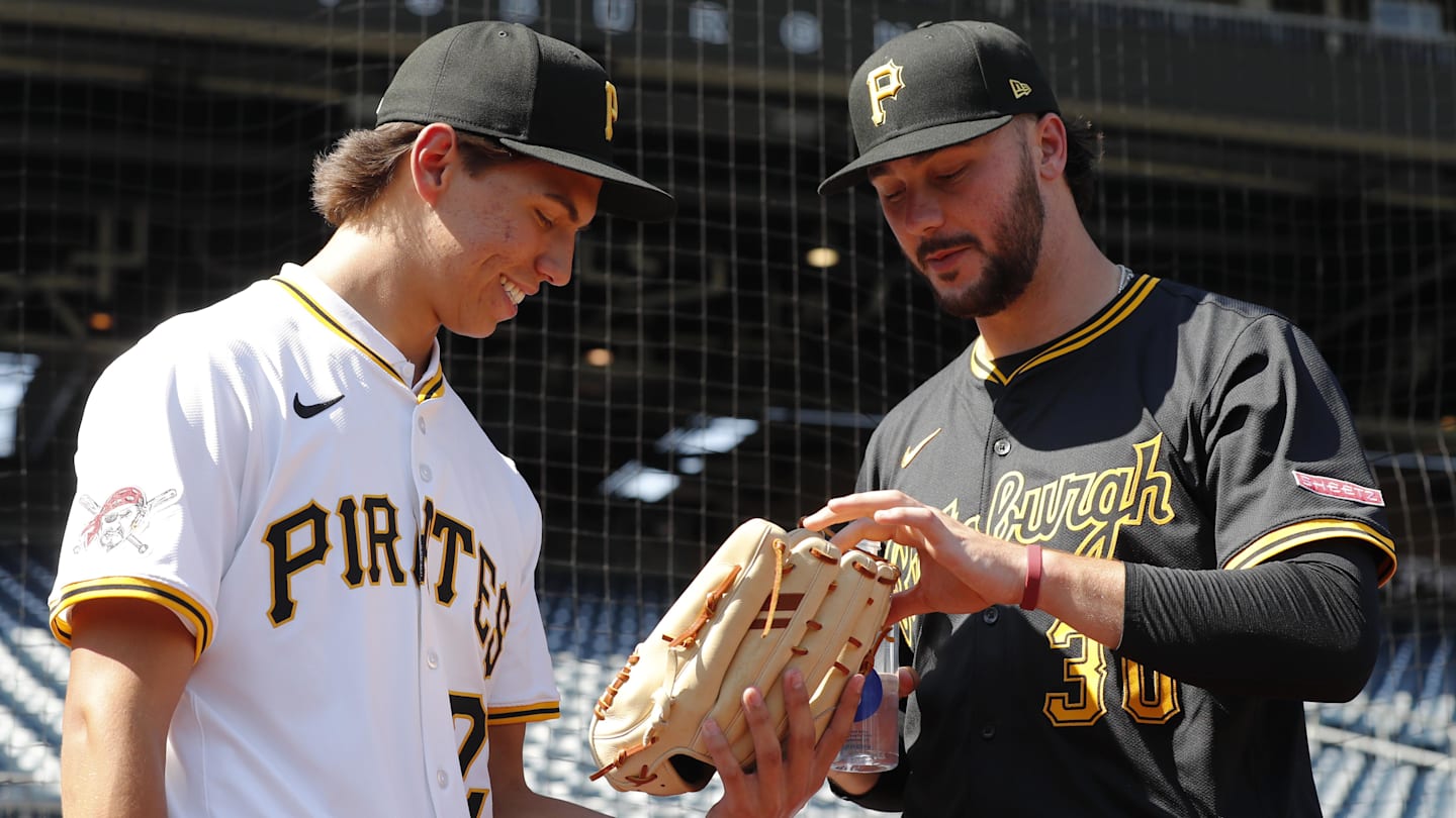 Jul 22, 2025; Pittsburgh, Pennsylvania, USA;  Seth Hernandez (left) the Pittsburgh Pirates first round and number six overall pick in the 2025 first year player draft looks at the glove of Pirates pitcher Paul Skenes (30) before the game against the Detroit Tigers at PNC Park. Mandatory Credit: Charles LeClaire-Imagn Images