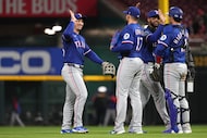 Texas Rangers' Wyatt Langford, center, high fives Nathan Eovaldi, center, at the conclusion...