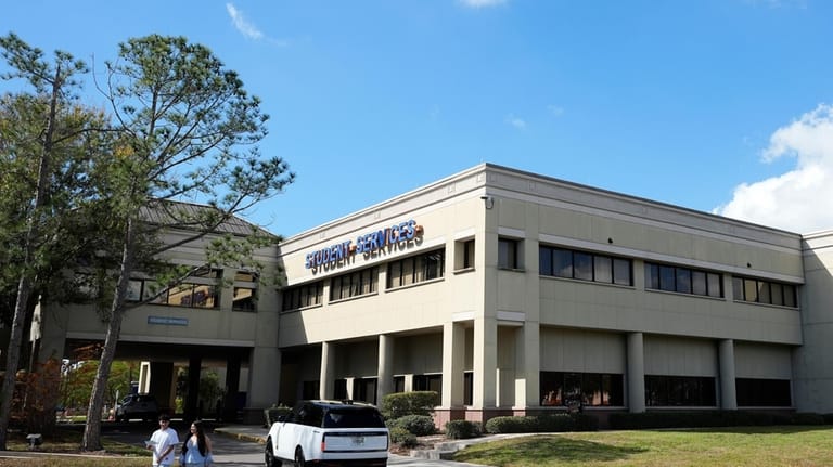 People walk in front of the student services building at...