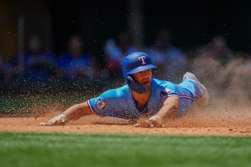 Texas Rangers' Josh Smith slides at home plate to score on a two-run single by Corey Seager...