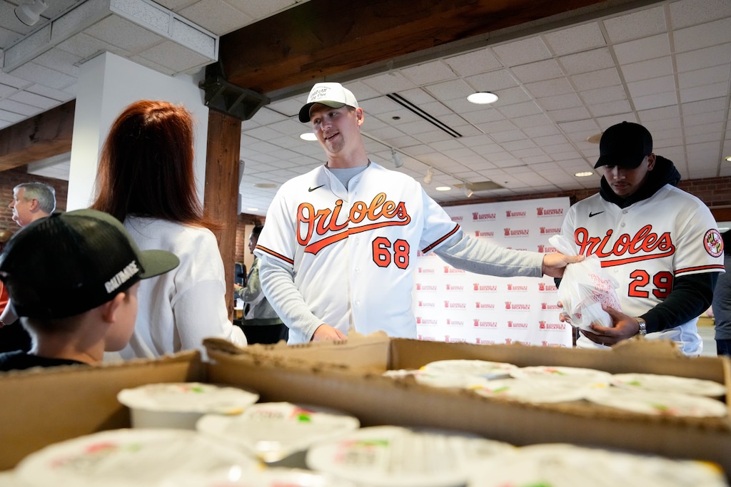 Baltimore Orioles pitcher Tyler Wells, center, hands off a donation bag to catcher Samuel Basallo during a Birdland Caravan event in the warehouse at Oriole Park at Camden Yards in Baltimore, Md., on Friday, January 23, 2026.
