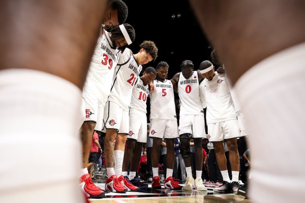 San Diego State players bow their heads before an exhibition game against UCLA at Viejas Arena on Friday, Oct. 17, 2025 in San Diego, California. (Meg McLaughlin / The San Diego Union-Tribune)