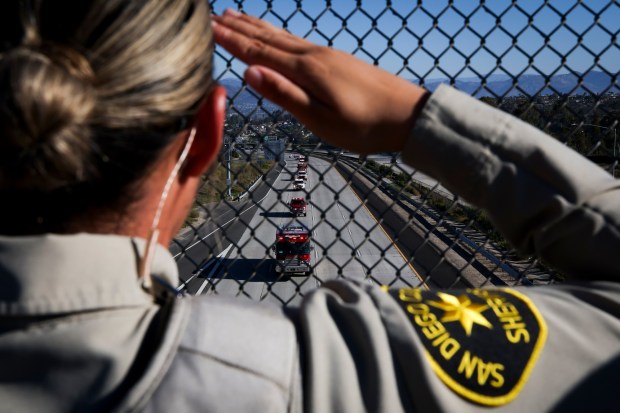 An officer with the San Diego County Sheriff's Department salutes the funeral procession following the hearse carrying the body of La Mesa police Officer Lauren Craven along southbound State Route 125 t SR 125 on Tuesday, Oct. 28, 2025 in El Cajon, California. (Meg McLaughlin / The San Diego Union-Tribune)
