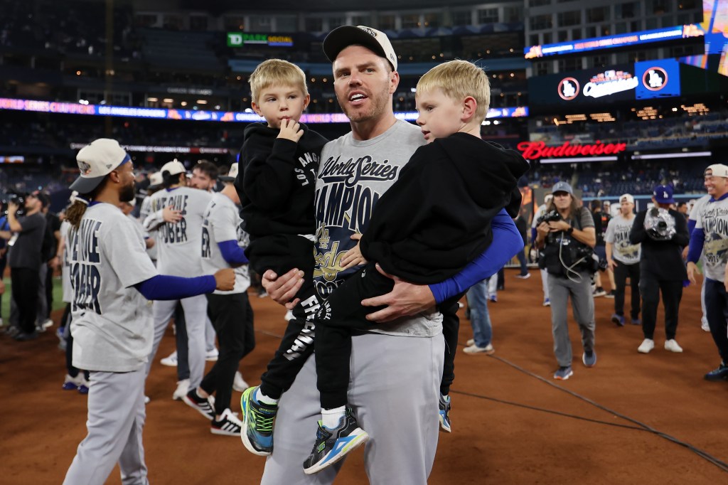 Freddie Freeman holding his two children at the 2025 World Series celebration.