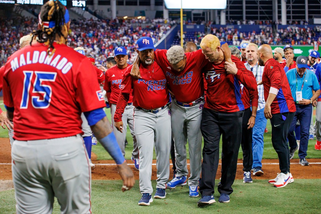 Puerto Rico pitcher Edwin Diaz is helped by pitching coach Ricky Bones and medical staff after a World Baseball Classic game.