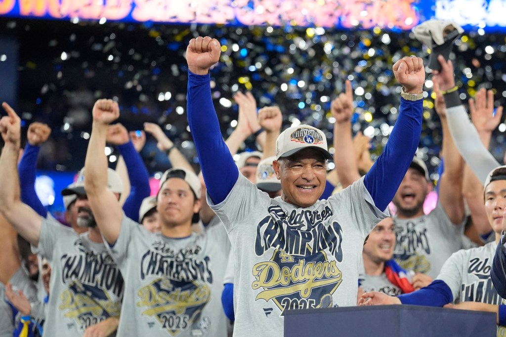 Los Angeles Dodgers manager Dave Roberts celebrating on a podium with his arms raised, surrounded by players also celebrating.