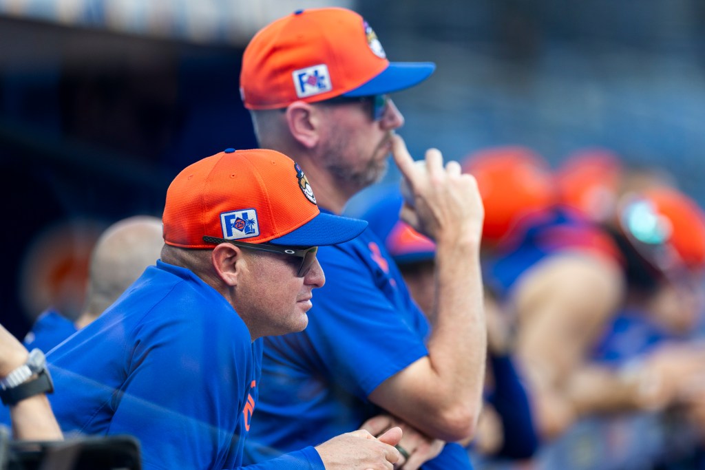 New York Mets manager Carlos Mendoza and pitching coach Jeremy Hefner in orange and blue caps.