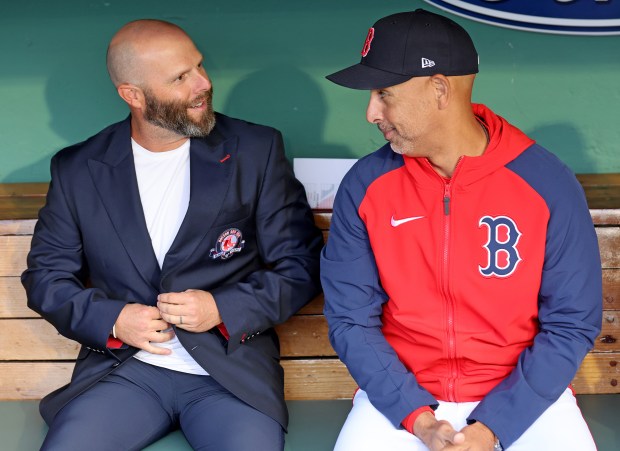 Red Sox Hall of Famer Dustin Pedroia, left, sits with manager Alex Cora in the dugout before a May 30, 2024 game at Fenway Park. (Photo By Matt Stone/Boston Herald)