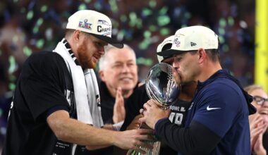 Feb 8, 2026; Santa Clara, CA, USA; Seattle Seahawks head coach Mike MacDonald and quarterback Sam Darnold (14) celebrate with the Vince Lombardi trophy on the podium after defeating the New England Patriots in Super Bowl LX at Levi's Stadium. Mandatory Credit: Mark J. Rebilas-Imagn Images
