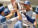 Toronto Blue Jays' Devon White (right) is greeted by teammates in the dugout after hitting a solo home run during a game in 1995.