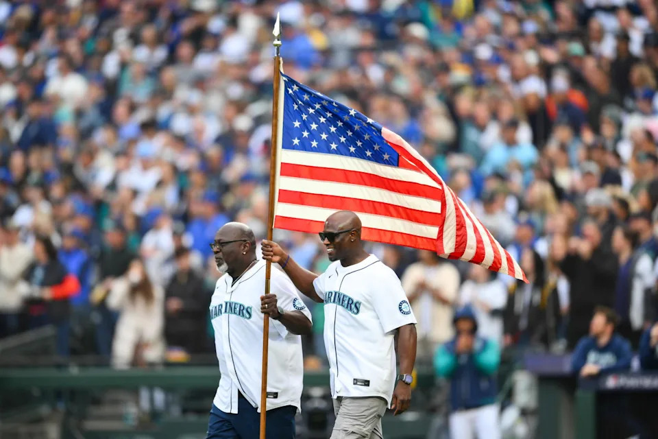 Former Seattle Mariners Mark McLemore and Mike Cameron carry the American flag out before game one of the ALDS round against the Detroit Tigers for the 2025 MLB playoffs at T-Mobile Park. Steven Bisig-Imagn Images