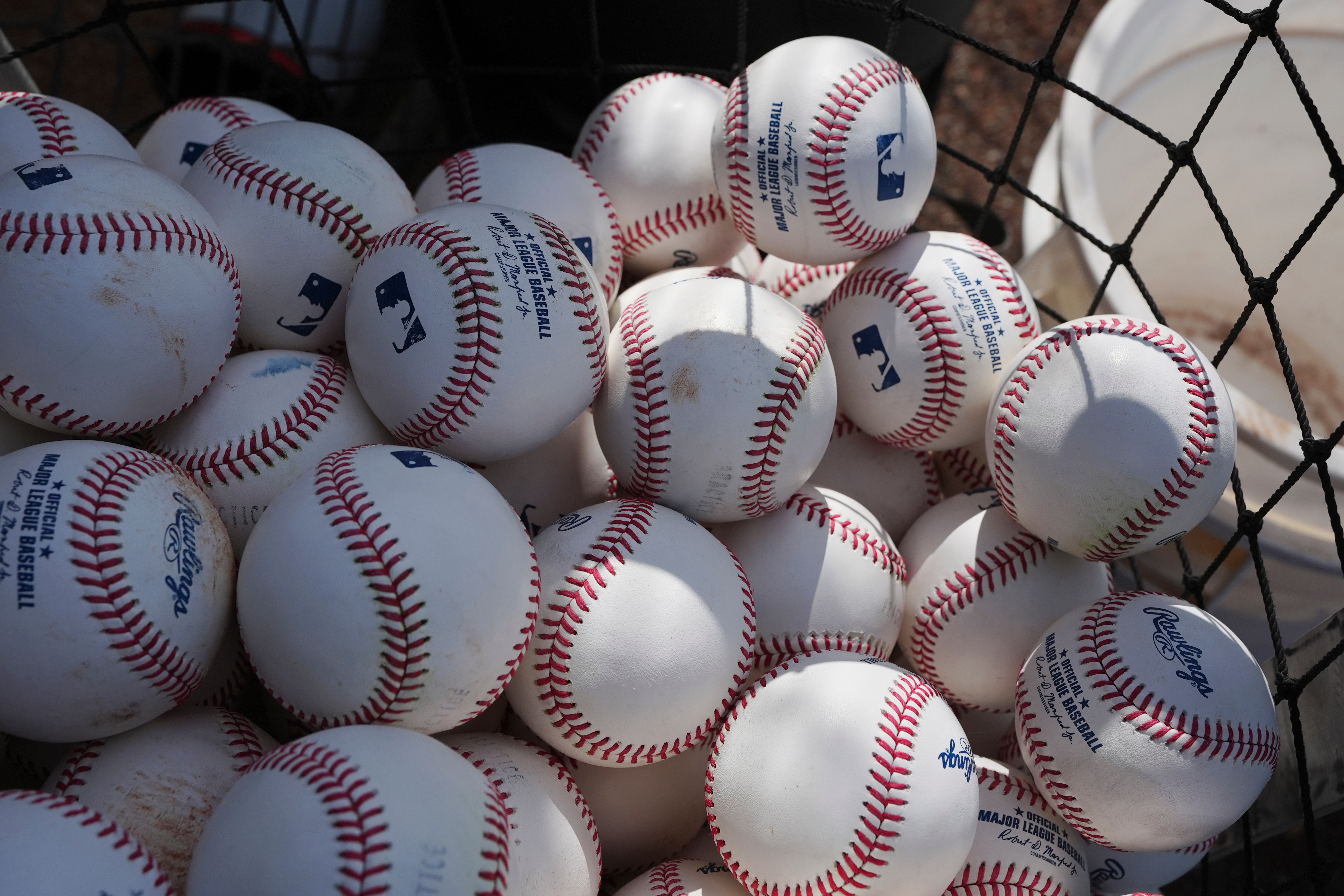 Dozens of baseballs fill a bin before being used for...