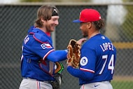 Texas Rangers catcher Willie MacIver talks with pitcher Leandro Lopez (74) after a bullpen...