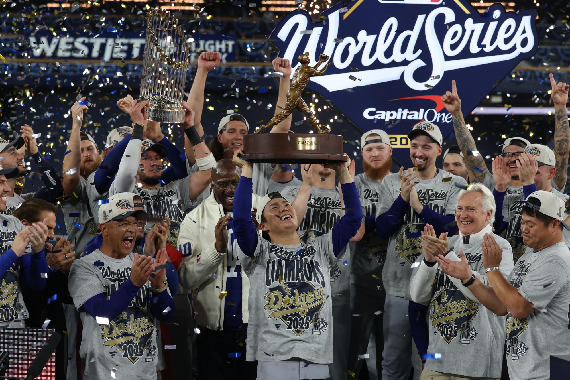 Dodgers pitcher Yoshinobu Yamamoto hoists the MVP trophy as they celebrate a World Series victory over the Toronto Blue Jays.