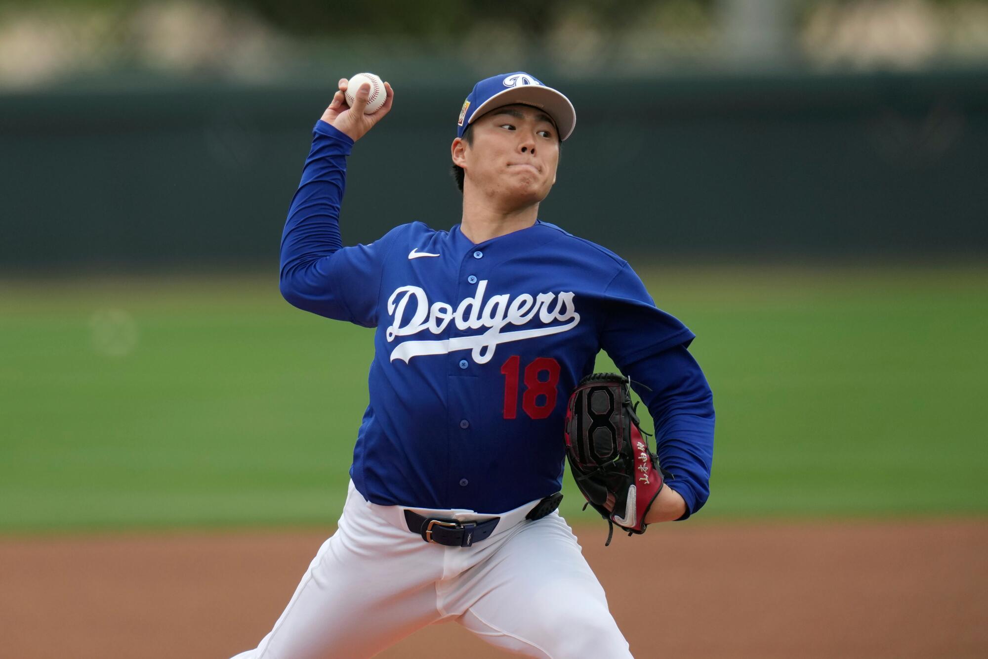 Dodgers pitcher Yoshinobu Yamamoto strides forward with his arm cocked as he delivers a pitch.