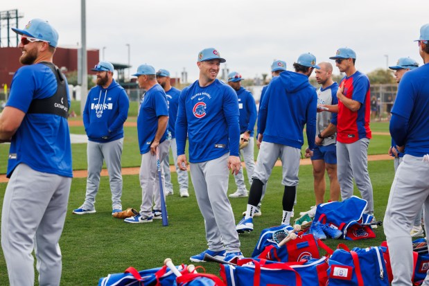 Alex Bregman (center) laughs after watching Seiya Suzuki throw a football to Pete Crow-Armstrong before warming up during the first day of the Cubs full-squad workout at spring training at Sloan Park on Feb. 16, 2026, in Mesa, Ariz. (Armando L. Sanchez/Chicago Tribune)