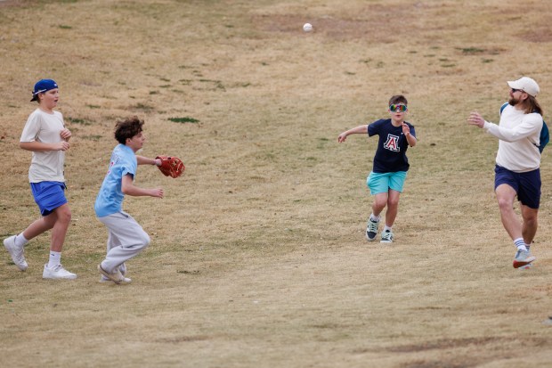 Fans chase a ball that cleared an outfield wall during Cubs batting practice at spring training on Feb. 18, 2026, at Sloan Park in Mesa, Ariz. (Armando L. Sanchez/Chicago Tribune)