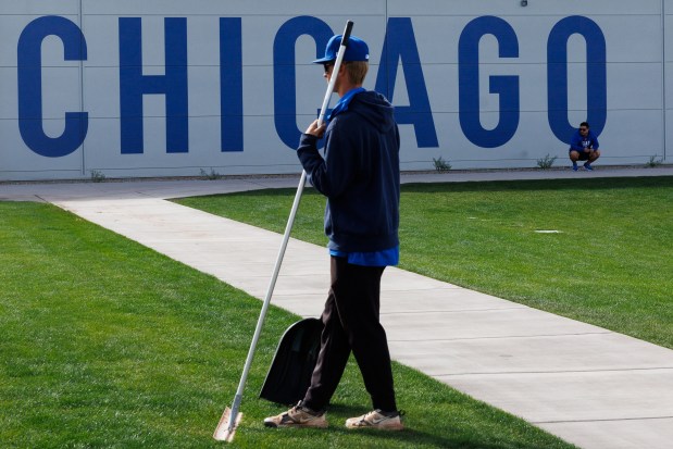 A member of the grounds crew watches Cubs pitchers throw in a practice bullpen area during spring training at Sloan Park on Feb. 18, 2026, in Mesa, Ariz. (Armando L. Sanchez/Chicago Tribune)