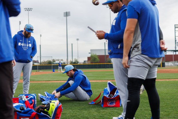 Dansby Swanson puts his shoes on before warming up during the first day of the Cubs full-squad workout at spring training at Sloan Park on Feb. 16, 2026, in Mesa, Ariz. (Armando L. Sanchez/Chicago Tribune)