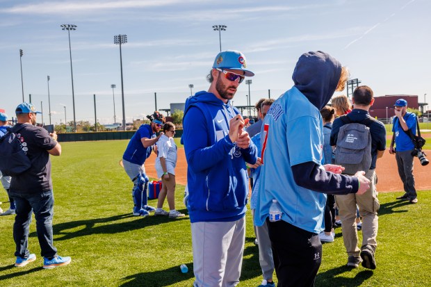 Cubs shortstop Dansby Swanson, left, signs a shirt for Jacob Frank, 19, after warmups during spring training at Sloan Park on Feb. 19, 2026, in Mesa, Ariz. (Armando L. Sanchez/Chicago Tribune)