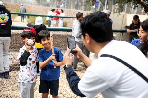 Friends Louis Suzuki, left, and Ryota Miyazawa pose for a picture with their ball and bat autographed by White Sox infielder Munetaka Murakami during spring training at Camelback Ranch on Monday, Feb. 16, 2026, in Glendale, Ariz. (Eileen T. Meslar/Chicago Tribune)