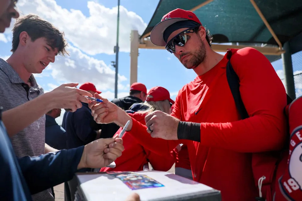 Josh Lowe signs trading cards for fans.