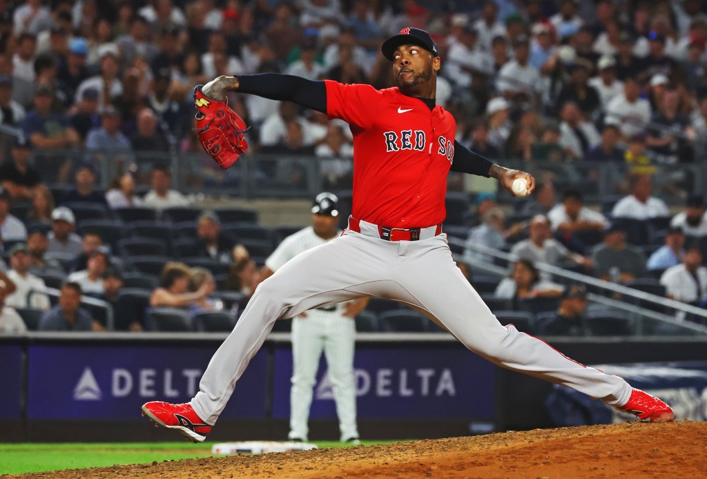 A Boston Red Sox pitcher in red and grey uniform throws a pitch.