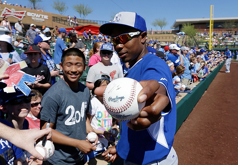 FILE - Kansas City Royals' Terrance Gore holds out a baseball he autographed for a fan prior to a spring training exhibition baseball game against the Colorado Rockies, Sunday, March 15, 2015, in Scottsdale, Ariz. (AP Photo/Ben Margot, File)