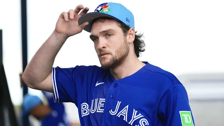 Trey Yesavage lifts his hat while wearing a blue Blue Jays t shir