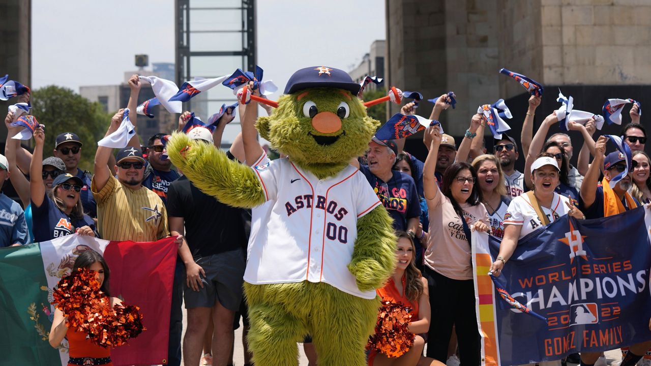 Houston Astros team mascot Orbit and fans, pose for a photo backdropped by the Monument to the Revolution in Mexico City, Thursday, April 25, 2024.(AP Photo/Fernando Llano)