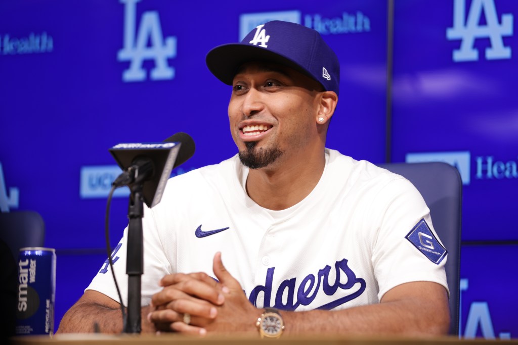 Edwin Díaz smiling at a press conference, wearing a white Dodgers jersey and blue Dodgers cap.