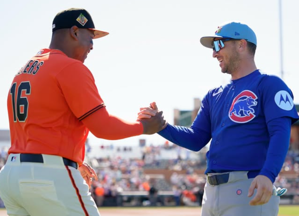 Two baseball players in uniform shaking hands on the field.