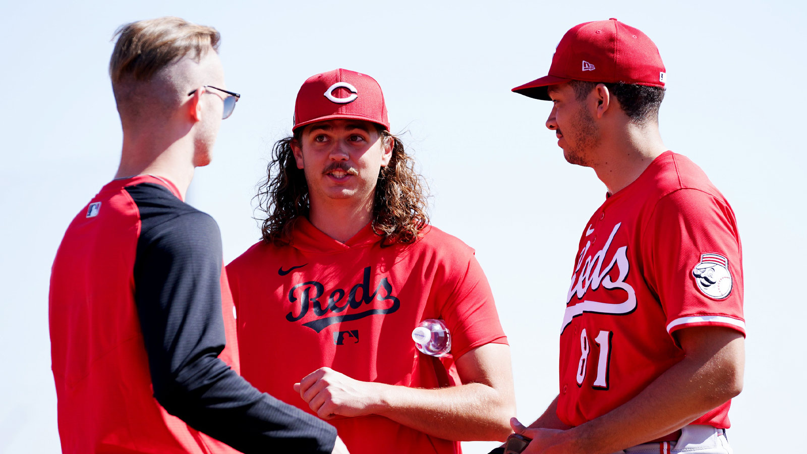 Cincinnati Reds pitcher Rhett Lowder (25), center, has a conversation with a staff member, left, and non-roster invitee Chase Burns (81) after a pitching session during spring training, Friday, Feb. 21, 2025, at the Cincinnati Reds Player Development Complex in Goodyear, Ariz.