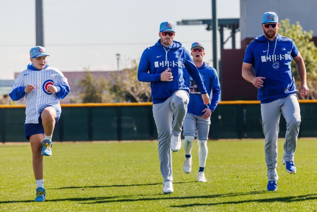 Anthony Castaldo, 12, an Advocate Children's Hospital patient, warms up next to Cubs left fielder Ian Happ after signing a one-day contract during spring training at Sloan Park on Feb. 19, 2026, in Mesa, Ariz. (Armando L. Sanchez/Chicago Tribune)