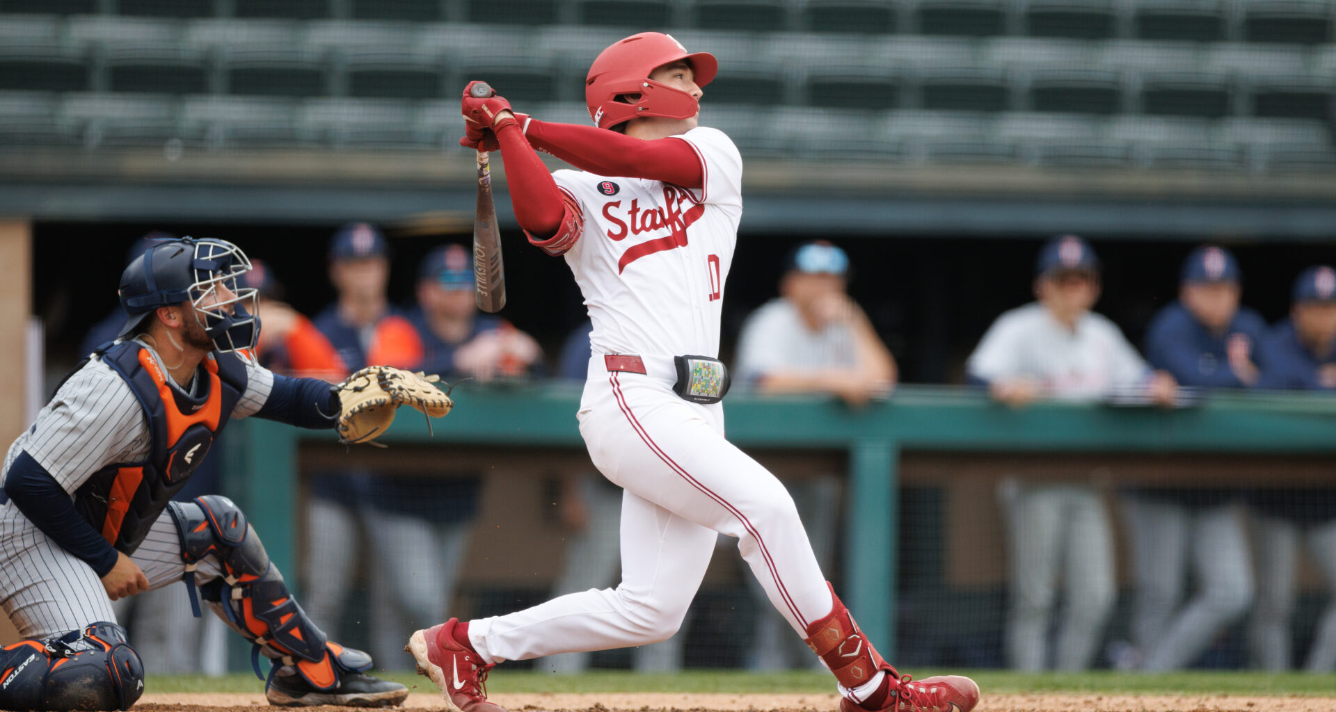 Baseball player swings at home plate.